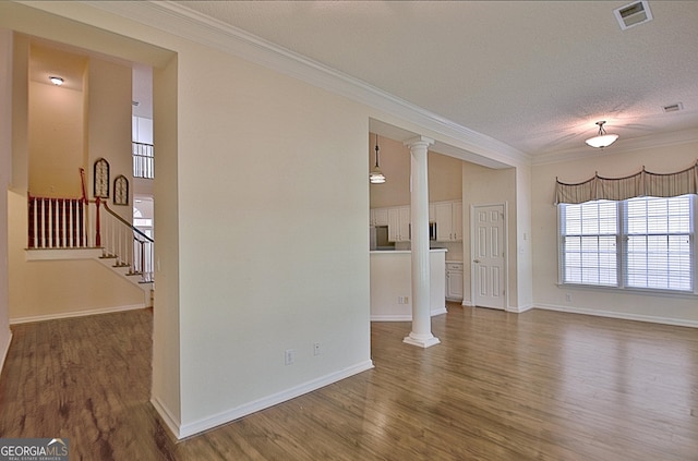 44 Arbor Way, Newnan, GA 30265 - unfurnished living room with ornamental molding, ornate columns, wood finished floors, stairs, and a textured ceiling