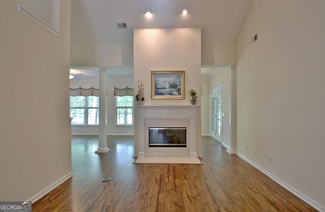 44 Arbor Way, Newnan, GA 30265 - unfurnished living room featuring decorative columns, a tile fireplace, wood finished floors, baseboards, and ornamental molding