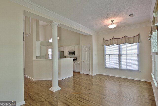 44 Arbor Way, Newnan, GA 30265 - unfurnished living room with wood finished floors, ornamental molding, plenty of natural light, a textured ceiling, and baseboards