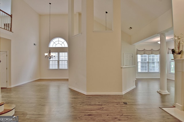 44 Arbor Way, Newnan, GA 30265 - foyer entrance featuring ornate columns, high vaulted ceiling, wood finished floors, baseboards, and a chandelier