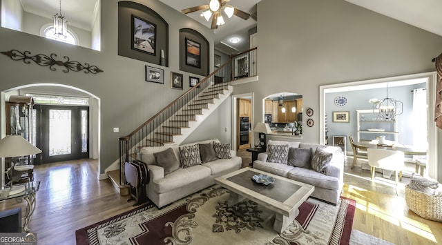 living area featuring healthy amount of natural light, stairs, a towering ceiling, and a chandelier