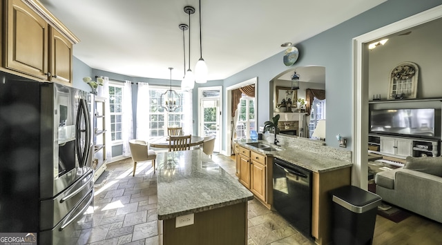 kitchen featuring stainless steel fridge, a sink, black dishwasher, a kitchen island, and a chandelier