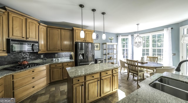 kitchen with black appliances, a sink, decorative backsplash, a chandelier, and decorative light fixtures