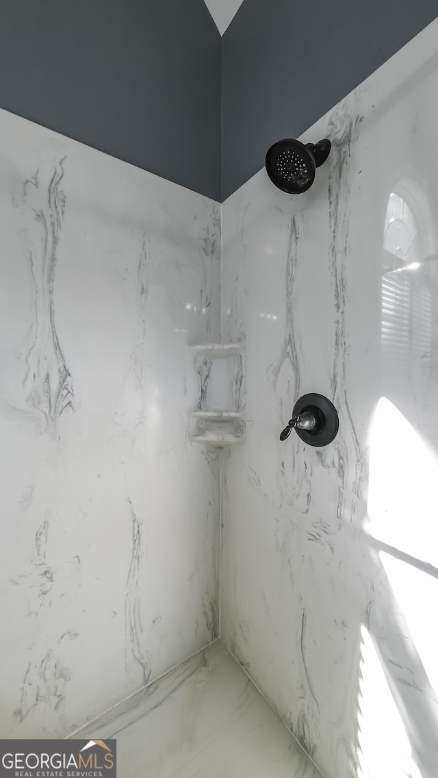 bathroom featuring a marble finish shower