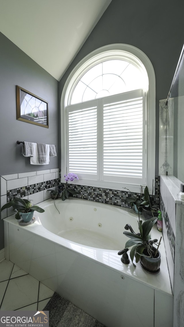 full bathroom with vaulted ceiling, a tub with jets, and plenty of natural light