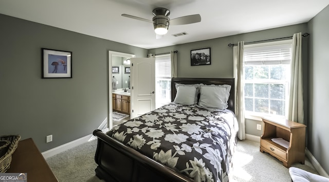 bedroom with light carpet, multiple windows, baseboards, and ensuite bath