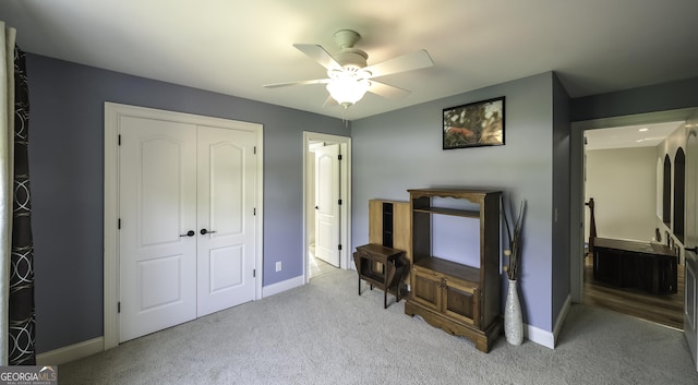 bedroom with light carpet, a closet, baseboards, and ceiling fan