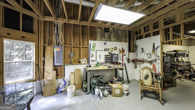 misc room featuring electric panel, a workshop area, and concrete floors