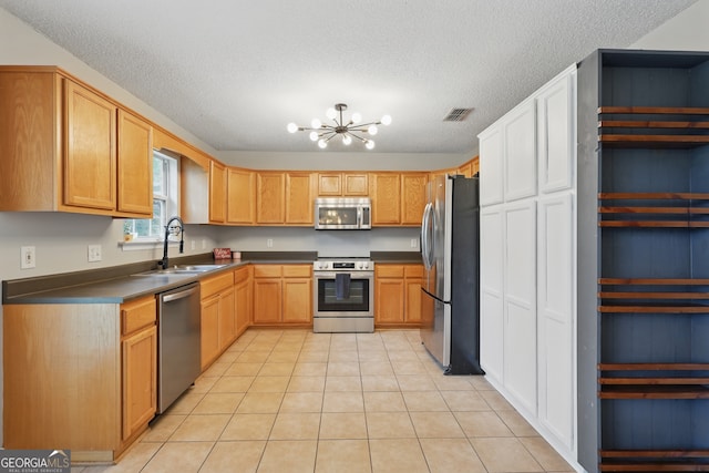 194 Retreat Pl, Woodbine, GA 31569 - kitchen with appliances with stainless steel finishes, a chandelier, a textured ceiling, light tile patterned flooring, and dark countertops