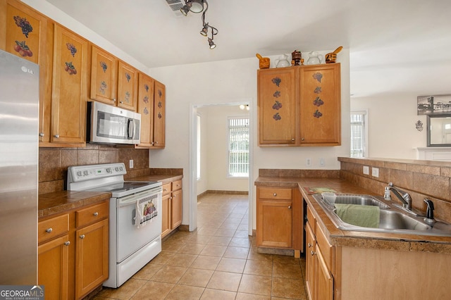 2770 Nautical Way, Villa Rica, GA 30180 - kitchen featuring appliances with stainless steel finishes, decorative backsplash, light tile patterned floors, a peninsula, and brown cabinets