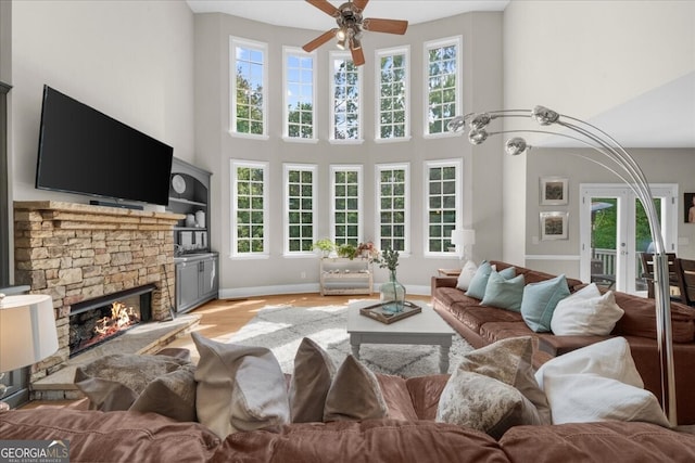 7049 Bennington Ln, Cumming, GA 30041 - living area with ceiling fan, a fireplace, a high ceiling, light wood finished floors, and french doors