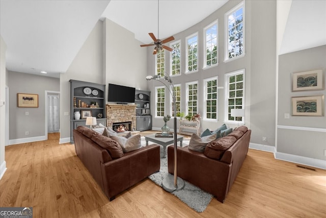 7049 Bennington Ln, Cumming, GA 30041 - living area featuring a high ceiling, a ceiling fan, a fireplace, and light wood-style floors