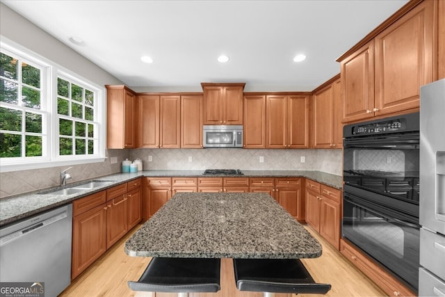 7049 Bennington Ln, Cumming, GA 30041 - kitchen featuring appliances with stainless steel finishes, light wood finished floors, stone counters, a kitchen island, and recessed lighting