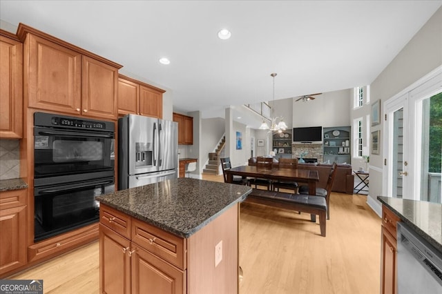 7049 Bennington Ln, Cumming, GA 30041 - kitchen with stainless steel appliances, light wood-style floors, open floor plan, dark stone counters, and a kitchen island