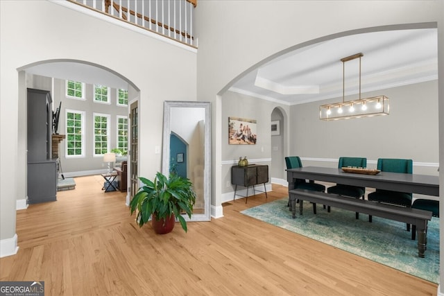 7049 Bennington Ln, Cumming, GA 30041 - dining space featuring light wood-style floors, ornamental molding, arched walkways, and a tray ceiling
