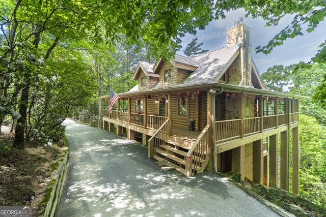 451 Pinecrest Rd, Sautee Nacoochee, GA 30571 - view of front of house featuring a porch, asphalt driveway, a chimney, log siding, and roof with shingles