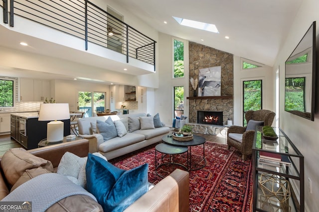 living room featuring wood finished floors, plenty of natural light, a stone fireplace, high vaulted ceiling, and recessed lighting