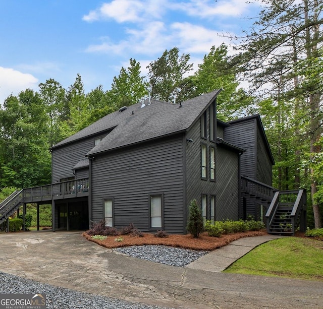view of home's exterior with stairway, a wooden deck, roof with shingles, and an attached garage