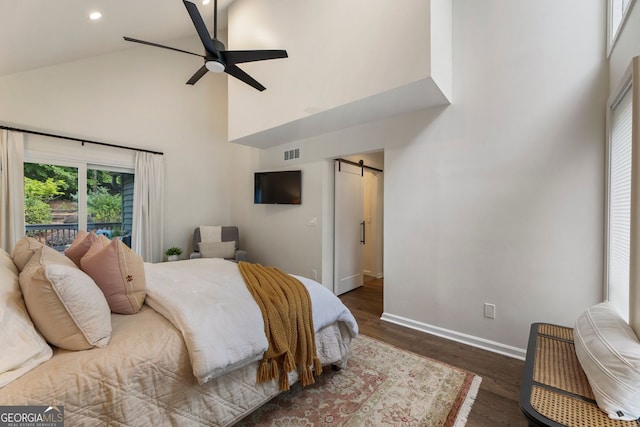 bedroom with high vaulted ceiling, a barn door, wood finished floors, baseboards, and recessed lighting