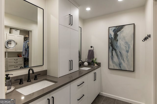 full bathroom featuring tile patterned flooring, double vanity, baseboards, a walk in closet, and recessed lighting