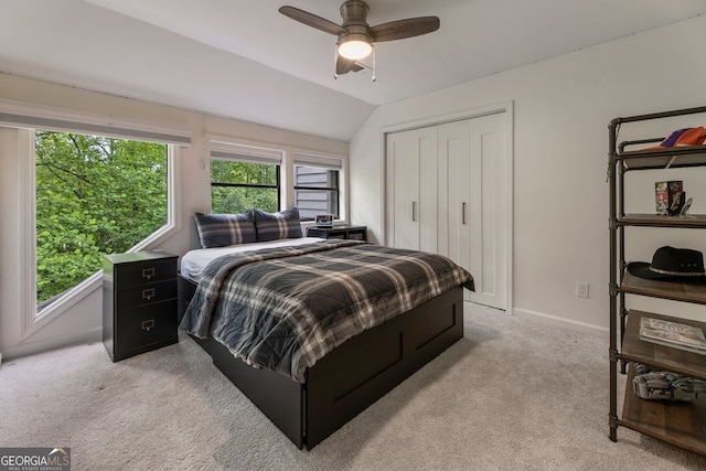 bedroom featuring light colored carpet, lofted ceiling, a closet, baseboards, and a ceiling fan