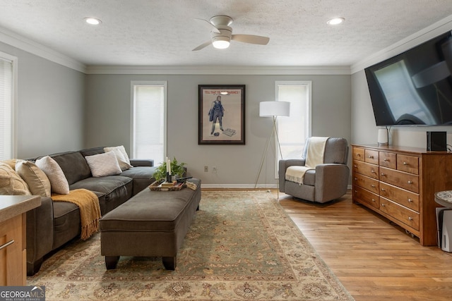 living room with a textured ceiling, light wood finished floors, a ceiling fan, crown molding, and baseboards