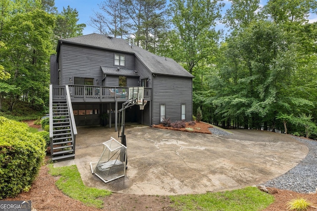 rear view of property with stairway, a wooden deck, and a shingled roof