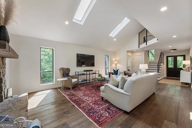 living area featuring high vaulted ceiling, a skylight, dark wood finished floors, recessed lighting, and stairs