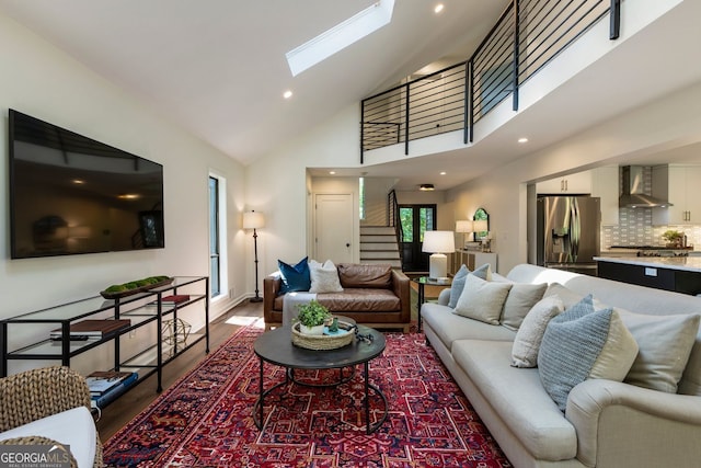 living room with stairway, a skylight, high vaulted ceiling, wood finished floors, and baseboards