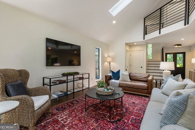 living area with a skylight, stairs, wood finished floors, high vaulted ceiling, and recessed lighting