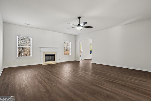 221 Cutbank Ct SW, Atlanta, GA 30331 - unfurnished living room featuring ceiling fan, dark wood-style flooring, arched walkways, a fireplace with flush hearth, and baseboards