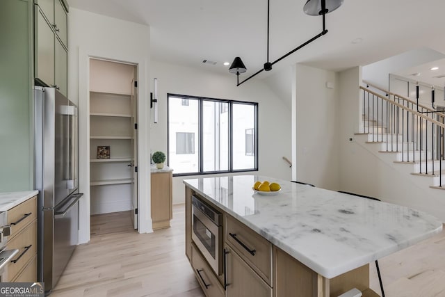 1954 8th St, Chamblee, GA 30341 - kitchen featuring appliances with stainless steel finishes, light wood finished floors, light stone counters, a kitchen island, and recessed lighting