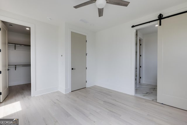 1954 8th St, Chamblee, GA 30341 - unfurnished bedroom with a barn door, baseboards, a walk in closet, and light wood-style floors