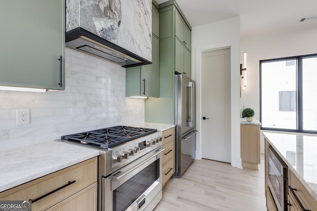 1954 8th St, Chamblee, GA 30341 - kitchen featuring green cabinetry, premium appliances, custom exhaust hood, backsplash, and light wood finished floors