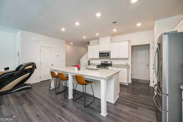 668 Isom Walk, Suwanee, GA 30024 - kitchen featuring appliances with stainless steel finishes, dark wood-style floors, white cabinetry, recessed lighting, and a breakfast bar