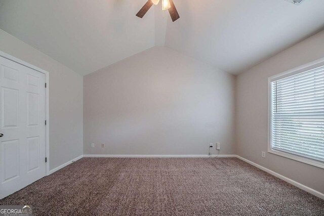 unfurnished bedroom featuring carpet, lofted ceiling, multiple windows, a ceiling fan, and baseboards