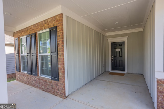 doorway to property featuring brick siding and a porch