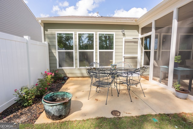 view of patio / terrace with fence, outdoor dining area, and a sunroom
