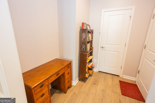 corridor with light wood-style floors and baseboards