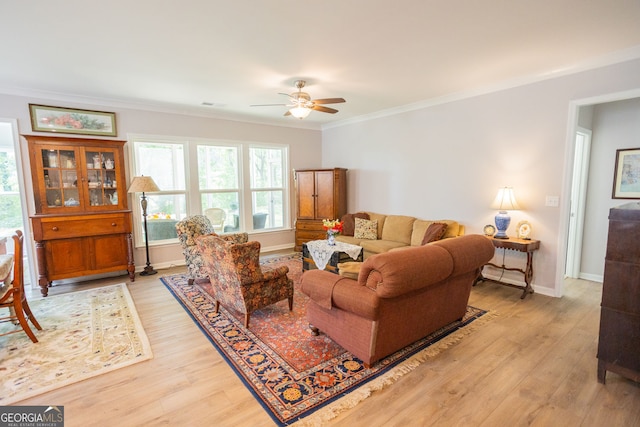 living area featuring a ceiling fan, light wood finished floors, ornamental molding, and baseboards