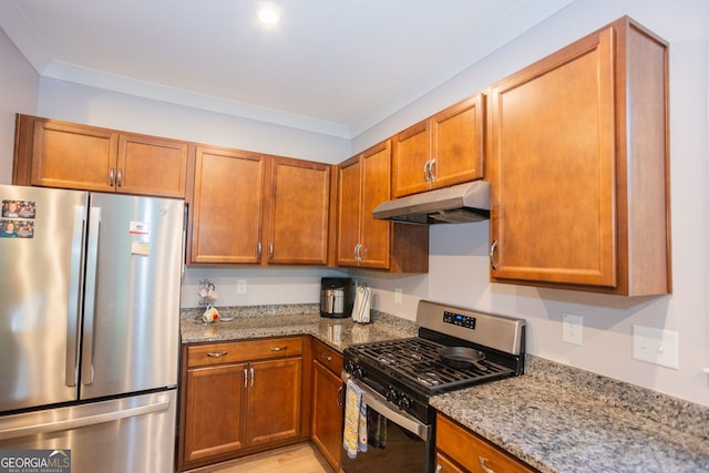 kitchen with appliances with stainless steel finishes, under cabinet range hood, light stone countertops, brown cabinets, and crown molding