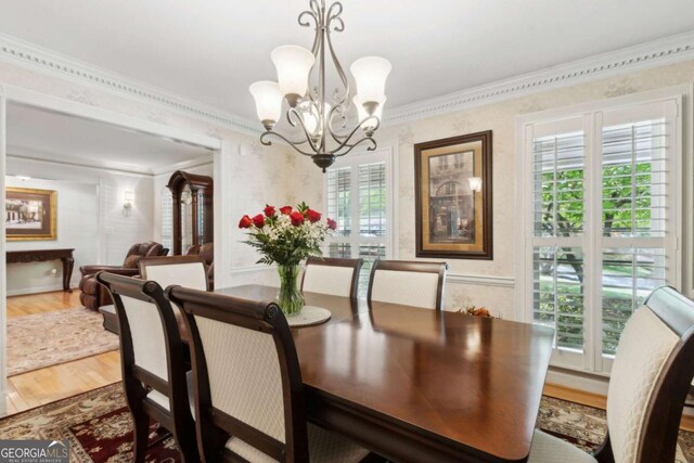 dining room featuring crown molding, a chandelier, wood finished floors, and wallpapered walls
