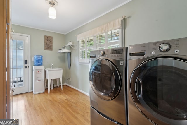 laundry area featuring independent washer and dryer, crown molding, light wood-style flooring, and baseboards