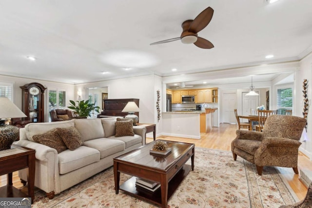 living area featuring crown molding, healthy amount of natural light, light wood-style flooring, recessed lighting, and ceiling fan