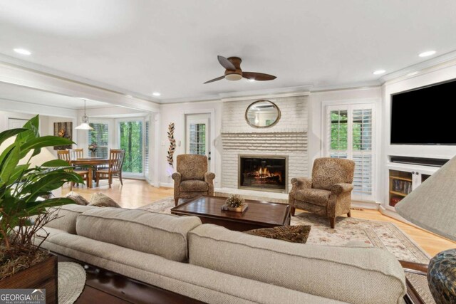 living room featuring crown molding, ceiling fan, plenty of natural light, a fireplace, and recessed lighting
