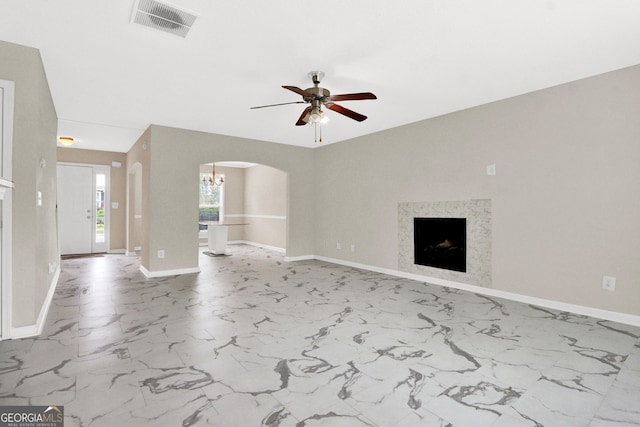 771 Franklin Mill Trce, Loganville, GA 30052 - unfurnished living room featuring arched walkways, a ceiling fan, marble finish floors, and a premium fireplace