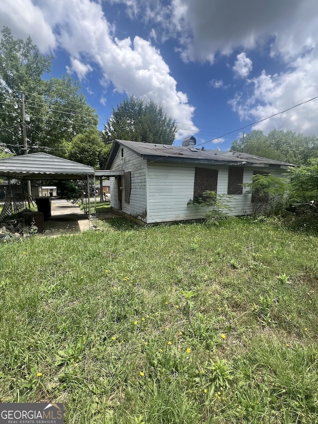 view of side of property with a detached carport and a lawn
