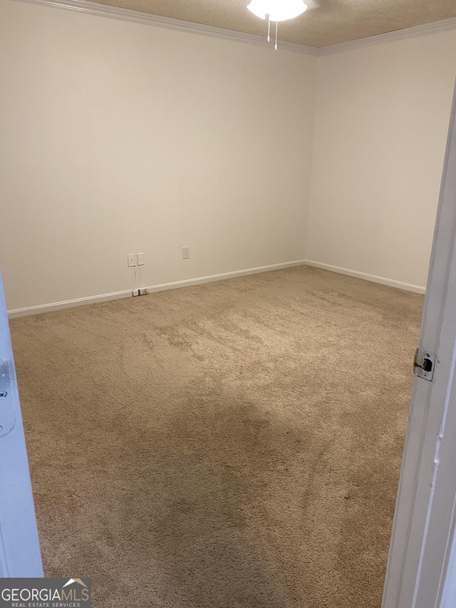 unfurnished room with carpet, crown molding, and baseboards