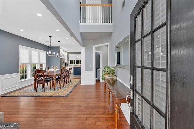 dining area featuring hardwood / wood-style floors, wainscoting, a chandelier, a decorative wall, and recessed lighting