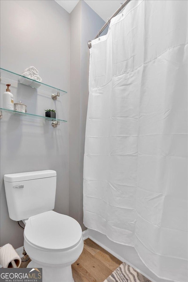 full bath with wood finished floors, a shower with shower curtain, and toilet